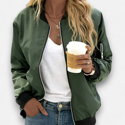 Person wearing a green bomber jacket holding a coffee cup on a white background