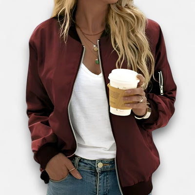 Person wearing a burgundy jacket holding a coffee cup against a white background