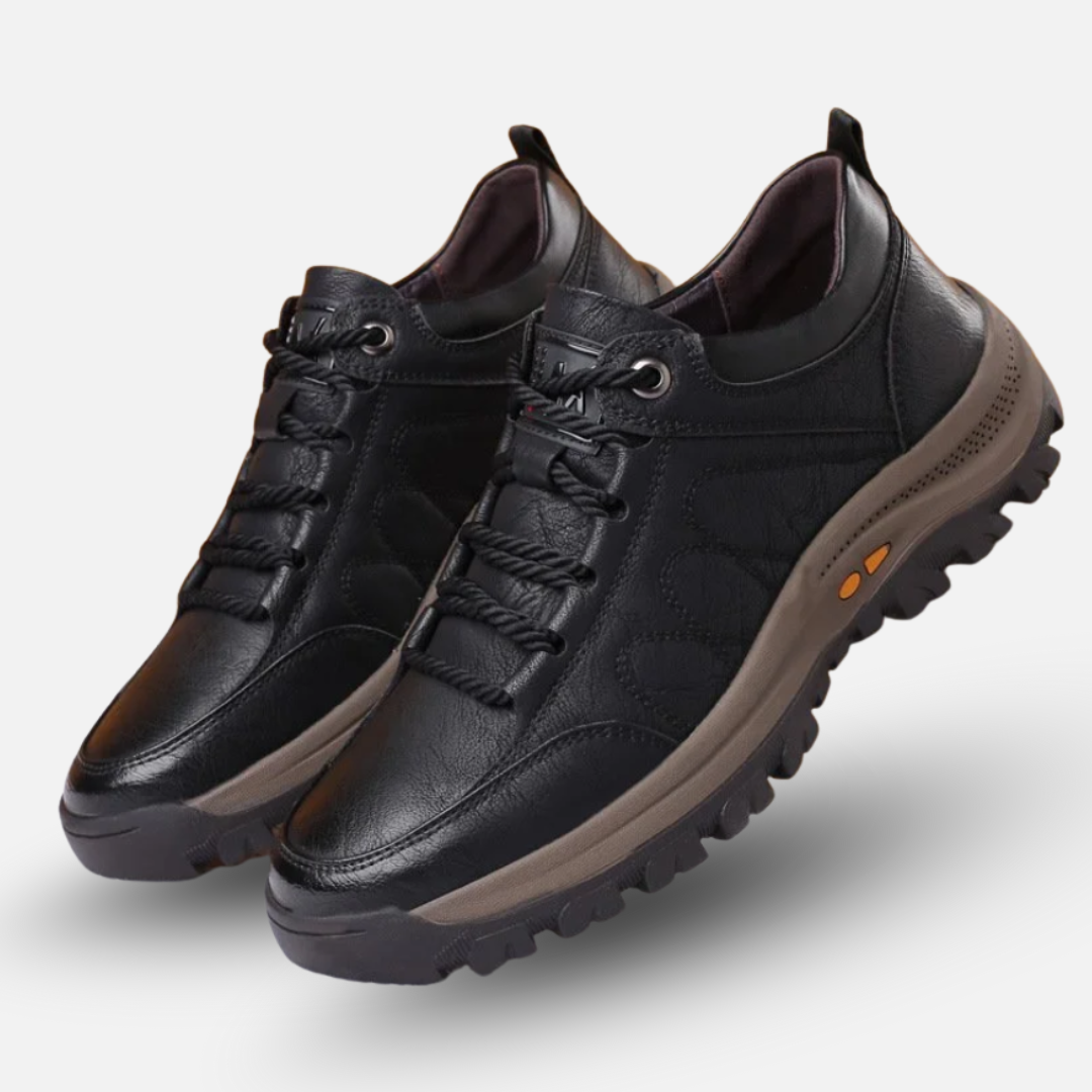 Black leather shoes with brown soles on a light gray background