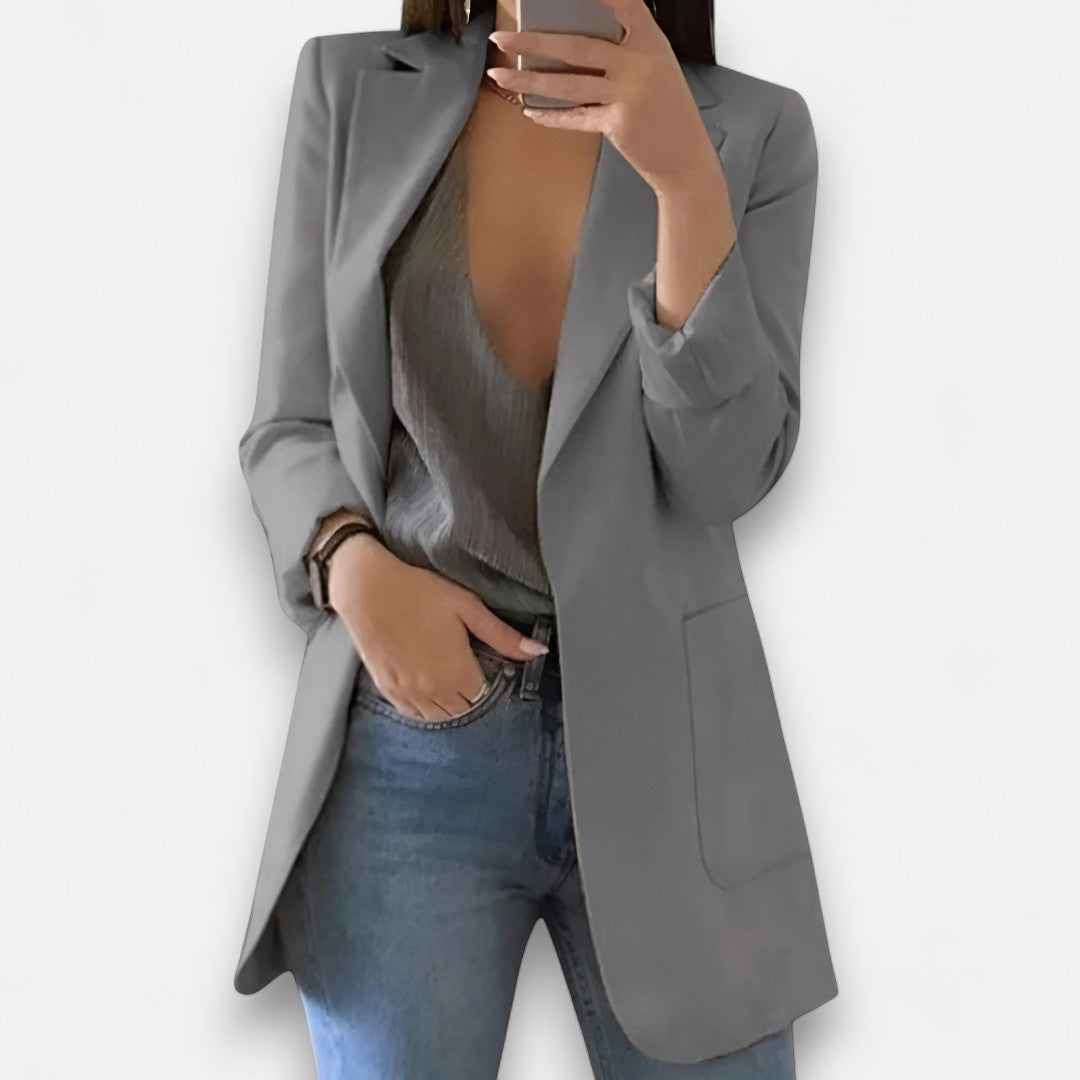 Person wearing a gray blazer over a gray top and blue jeans on a white background