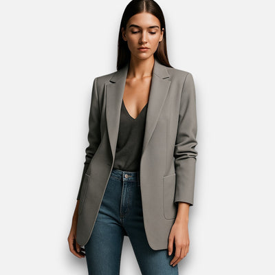 Woman wearing a gray blazer and blue jeans on a white background
